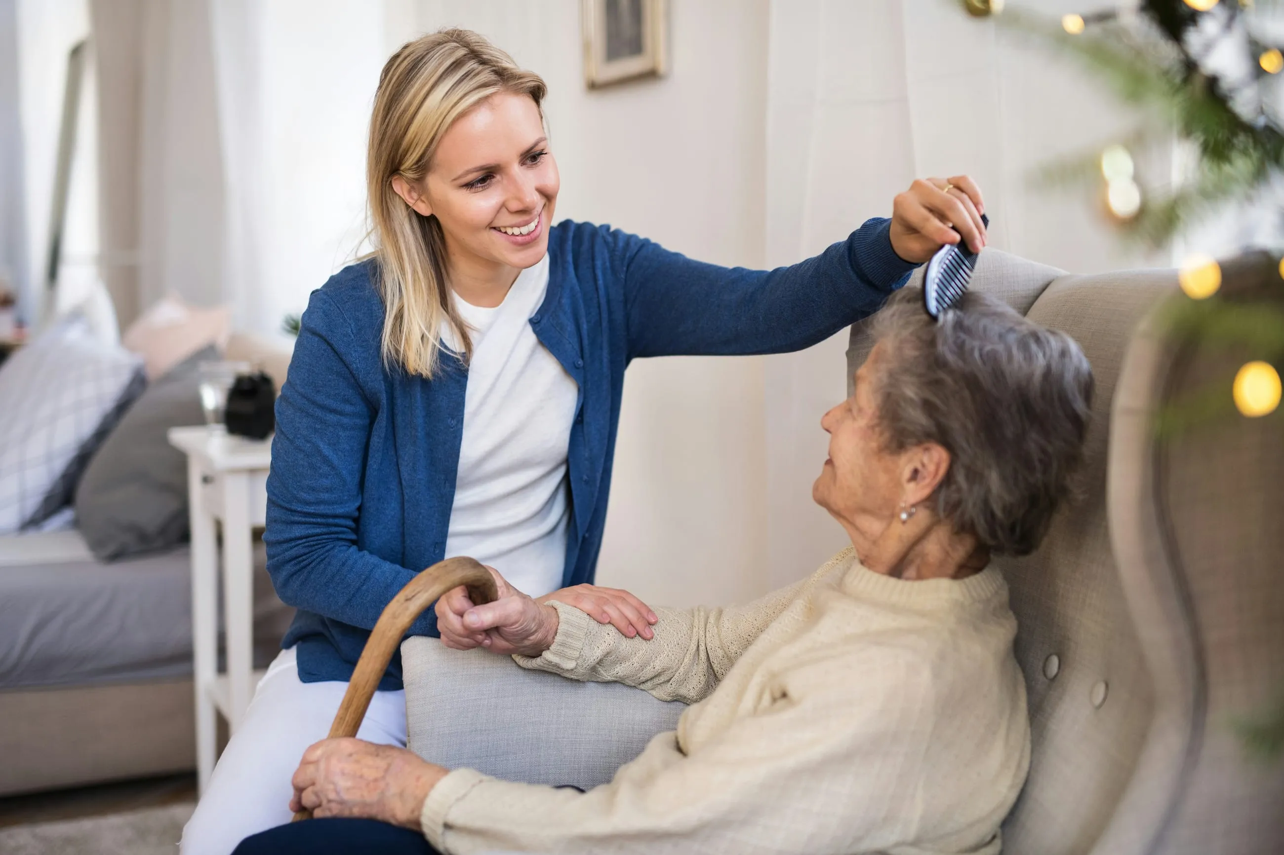 A home carer brushing an older woman's hair in her living room